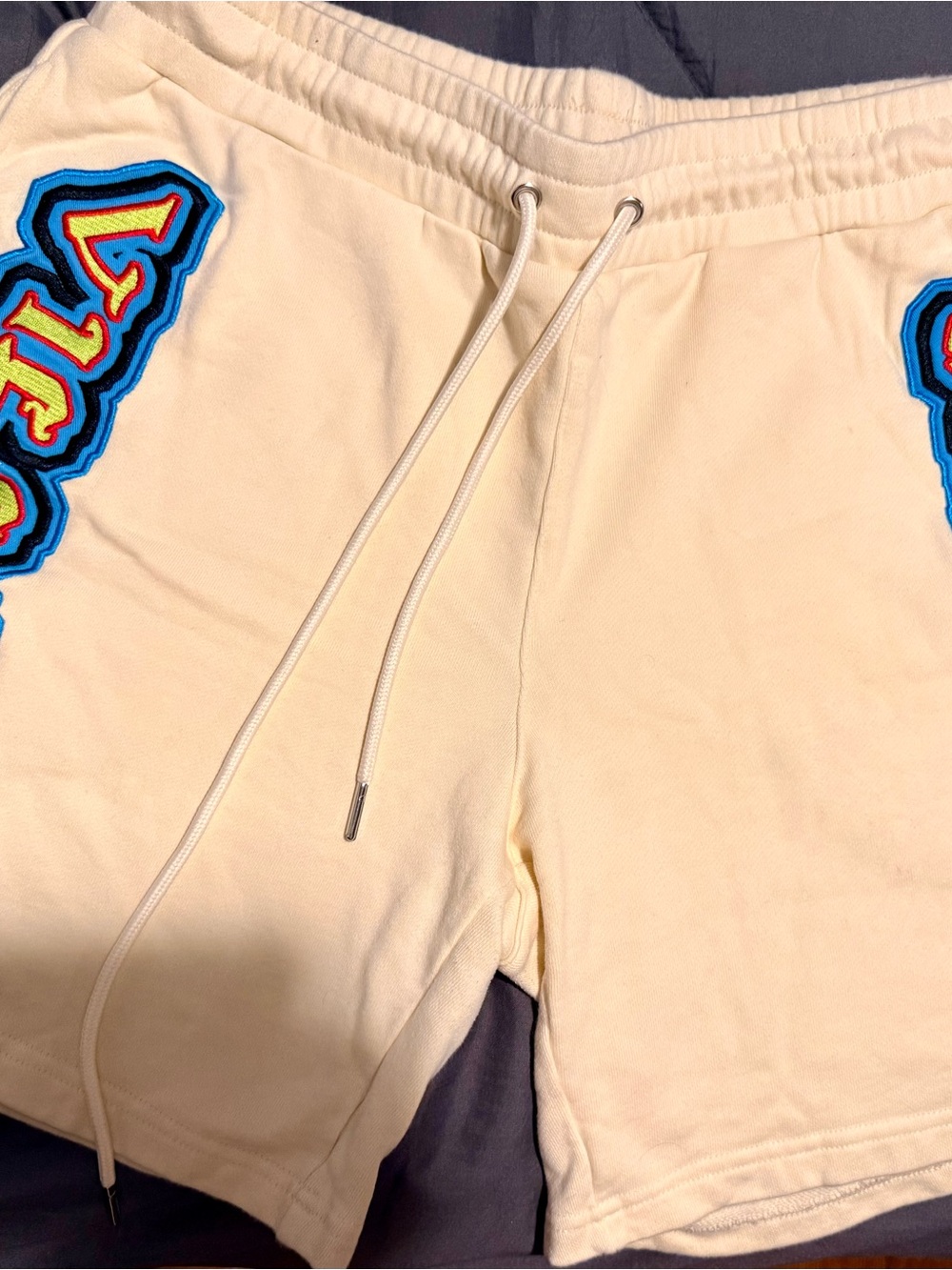 Cream Athletic Drawstring Shorts with Blue Patch Accents